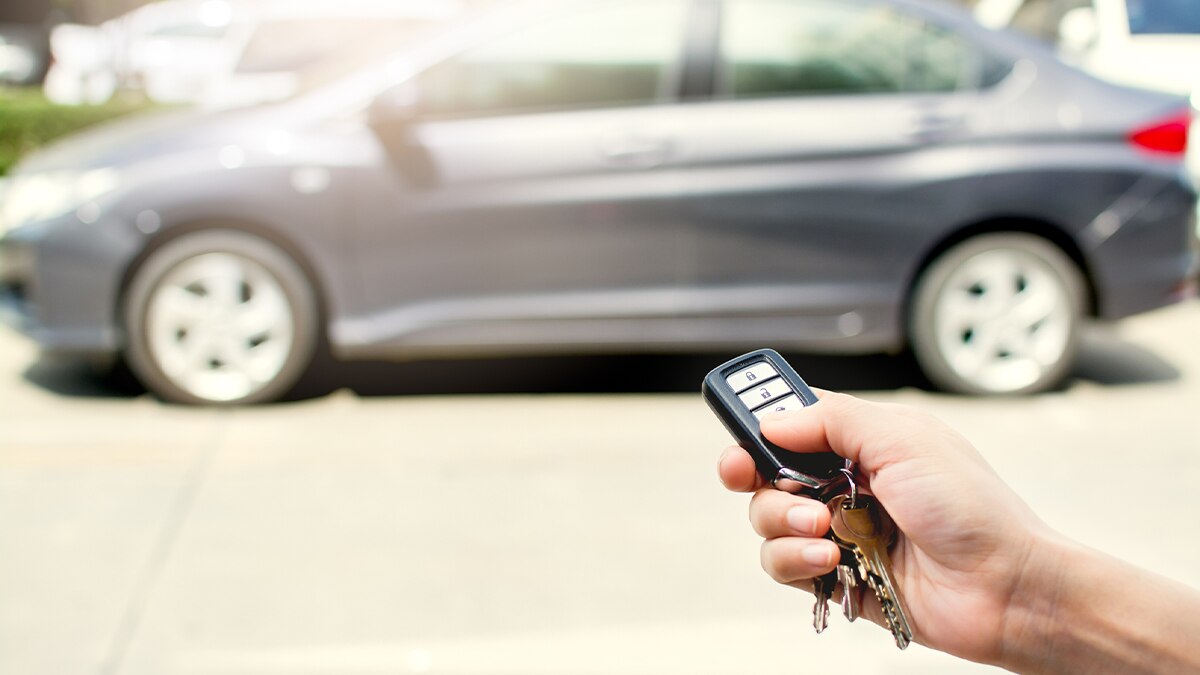 A person pointing a key fob at a vehicle